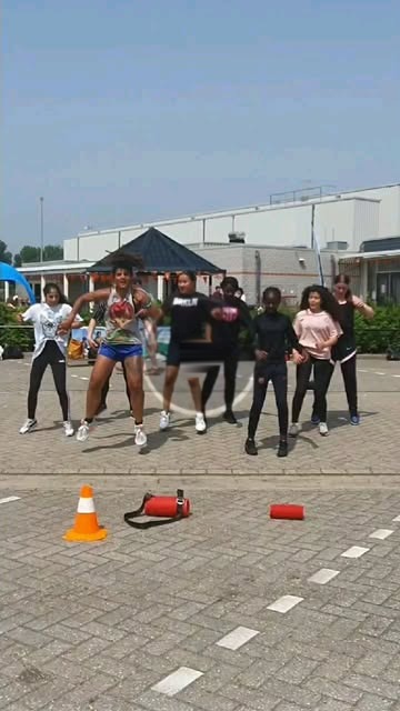 Een groep danst in een rij op een schoolplein